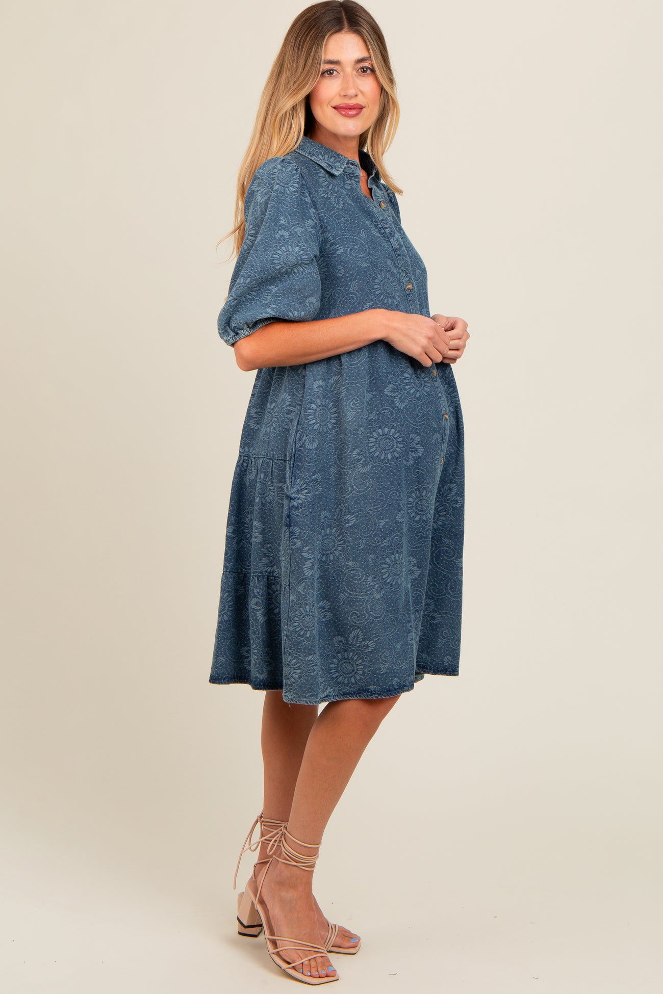 woman wearing a blue floral maternity dress with short sleeves and a button-down front, showcasing her baby bump