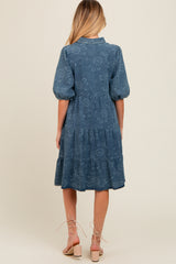 woman wearing a blue maternity dress with puff sleeves and tiered design, showing the back view