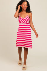 woman wearing a pink and white striped crochet dress with a fitted bodice and flared skirt, smiling and walking