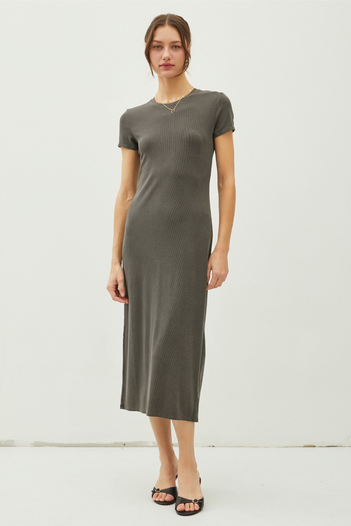 woman wearing a dark grey short sleeve ribbed midi dress and black heeled sandals