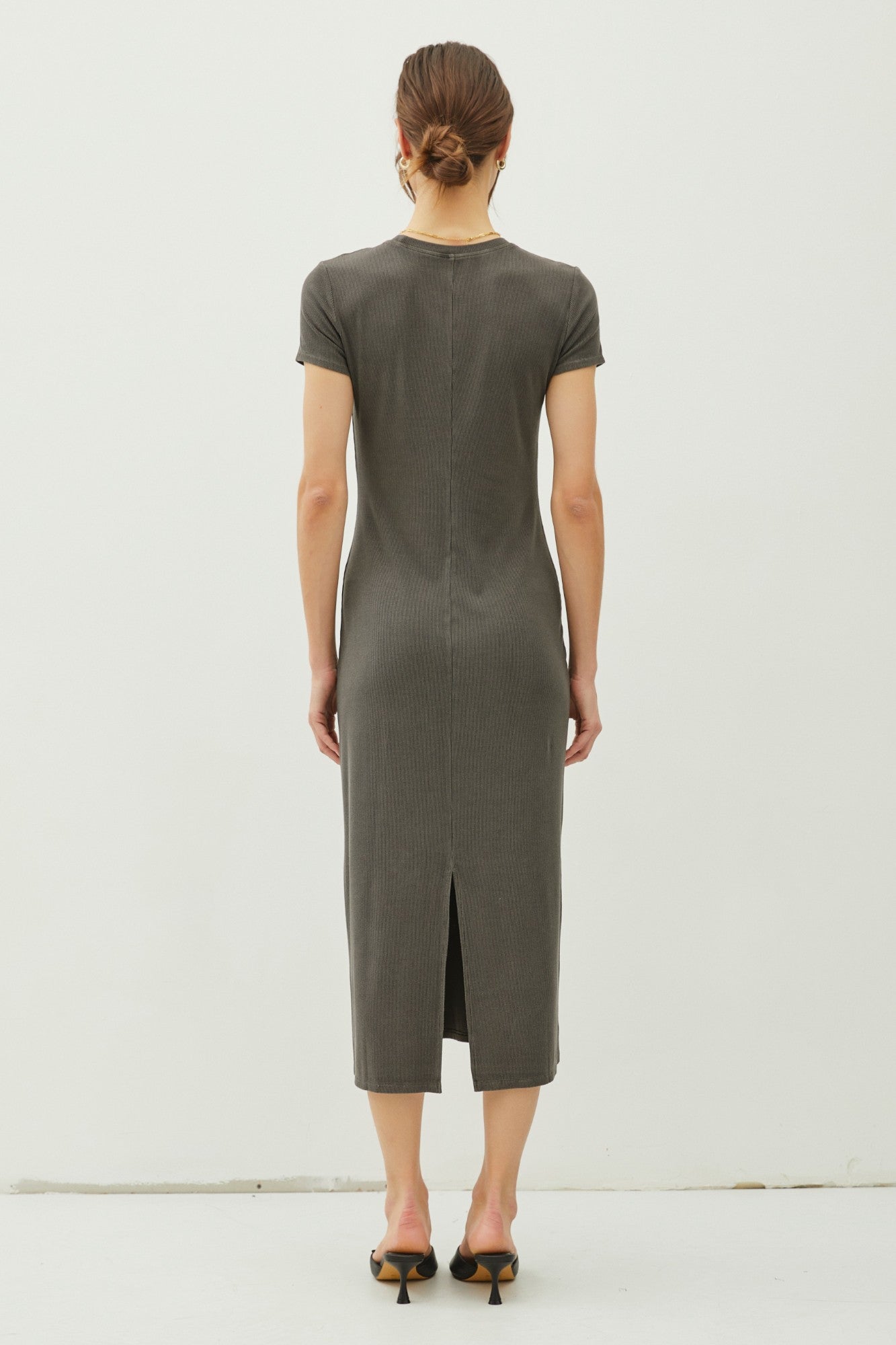 woman wearing a gray ribbed midi dress with short sleeves and a back slit detailing, view from the back