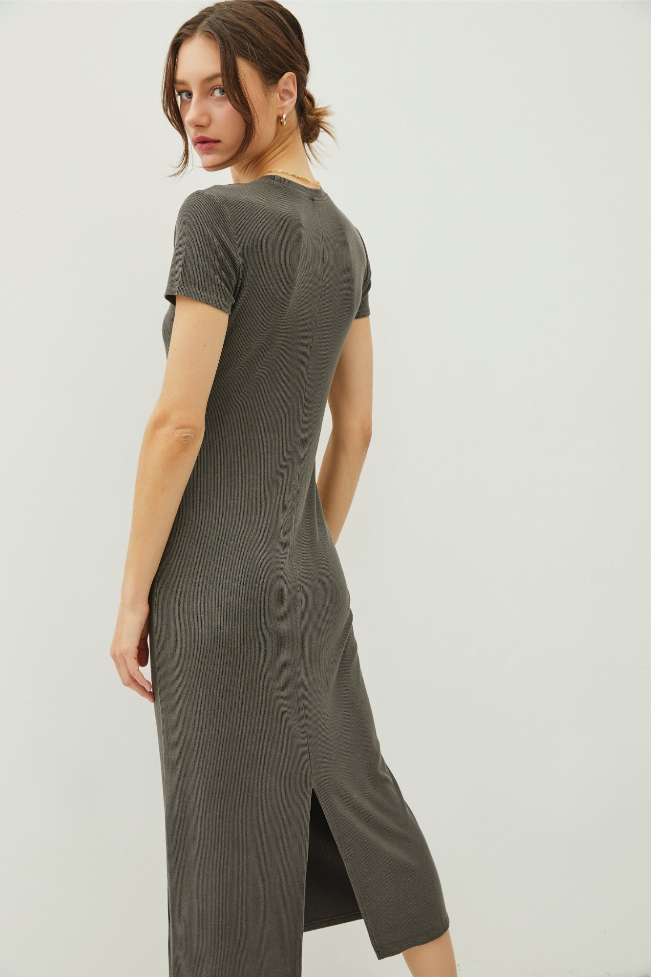 woman wearing an olive green ribbed midi dress with short sleeves and a side slit