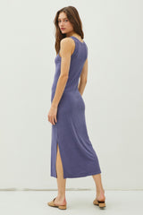 woman wearing a purple ribbed midi dress with side slits and a fitted silhouette, standing with her back to the camera