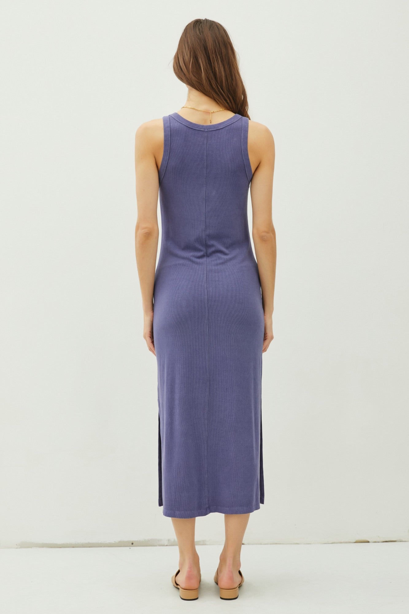 woman wearing a purple sleeveless midi dress with a side slit, viewed from the back