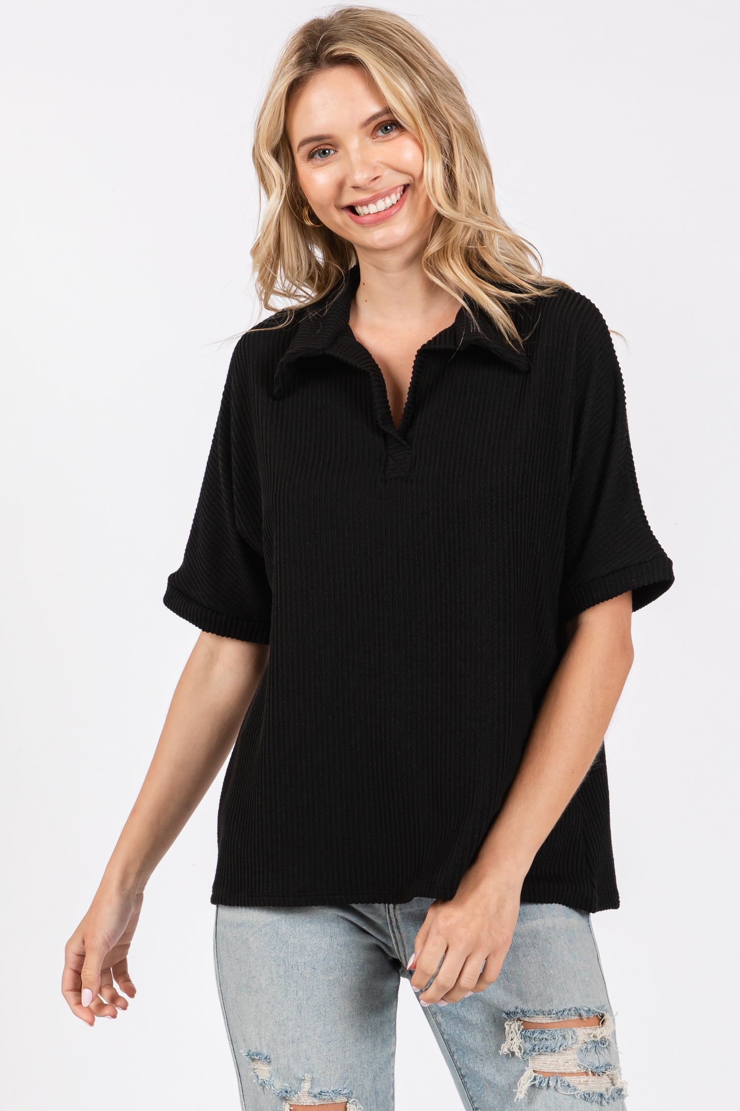 woman wearing a black short sleeve polo-style top with a relaxed fit and a collared neckline