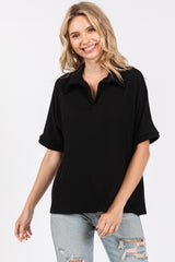 woman wearing a black short sleeve polo-style top with a relaxed fit and a collared neckline