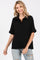 woman wearing a black short sleeve polo-style top with a relaxed fit and a collared neckline
