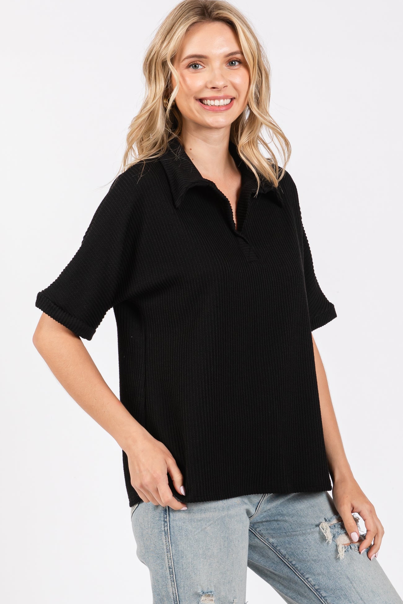 woman wearing a black ribbed polo style top with a collar and short sleeves