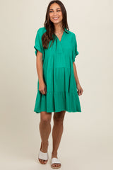 woman wearing a green short sleeve maternity dress with a tiered design and v-neckline