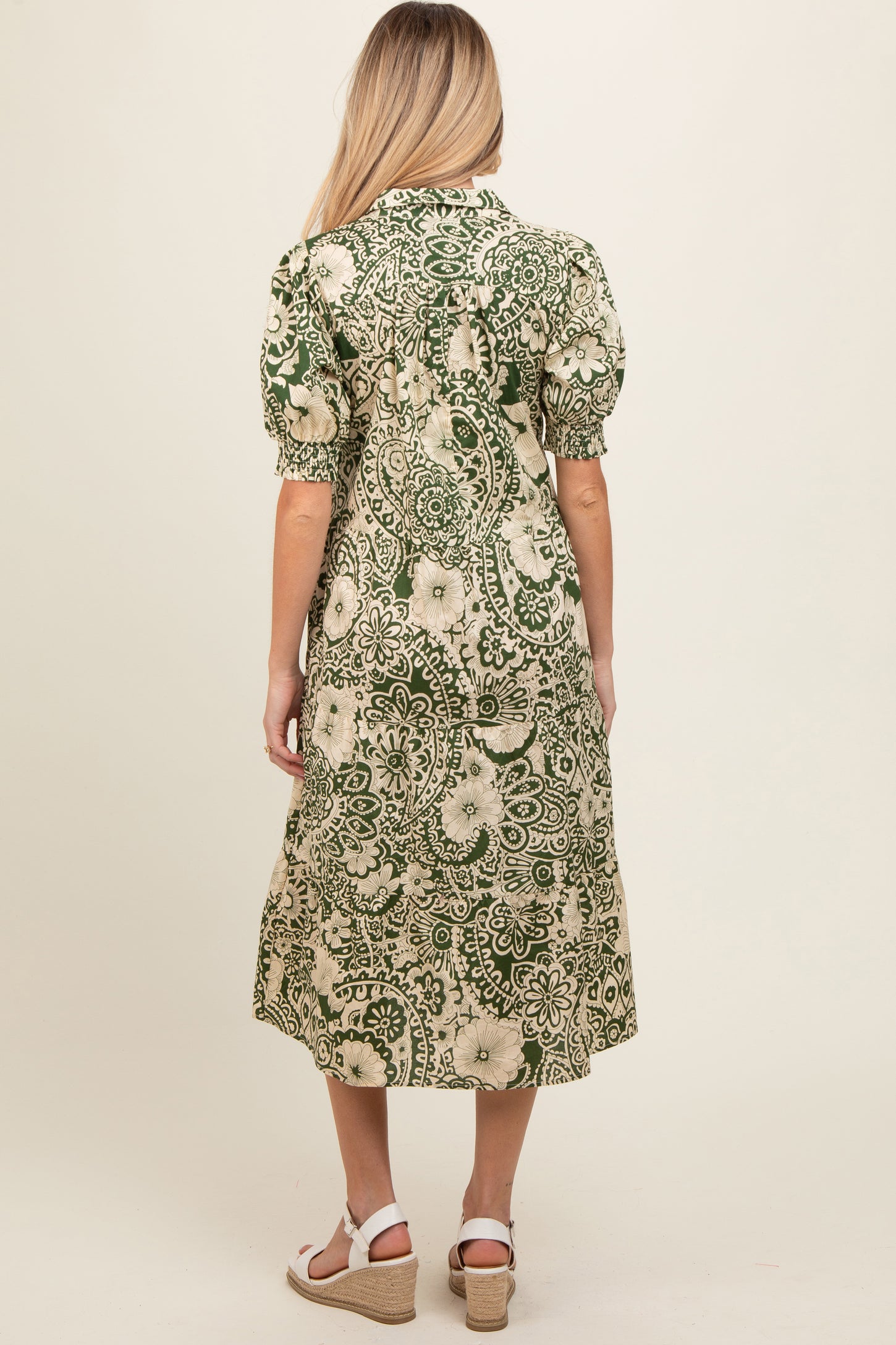 woman wearing a green floral print maternity dress with short puff sleeves, shown from the back