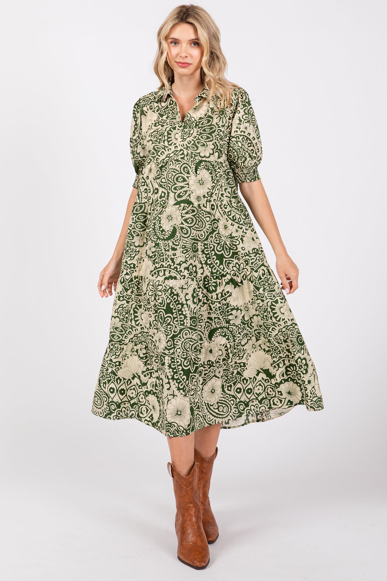 woman wearing a green and beige patterned midi dress with puff sleeves and brown cowboy boots