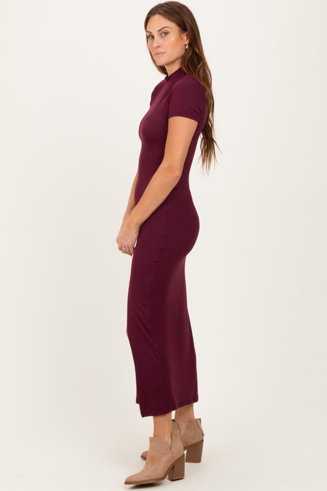 woman wearing a burgundy short sleeve fitted midi dress and beige heeled ankle boots, posing sideways