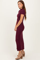 woman wearing a burgundy short sleeve fitted midi dress and beige heeled ankle boots, posing sideways