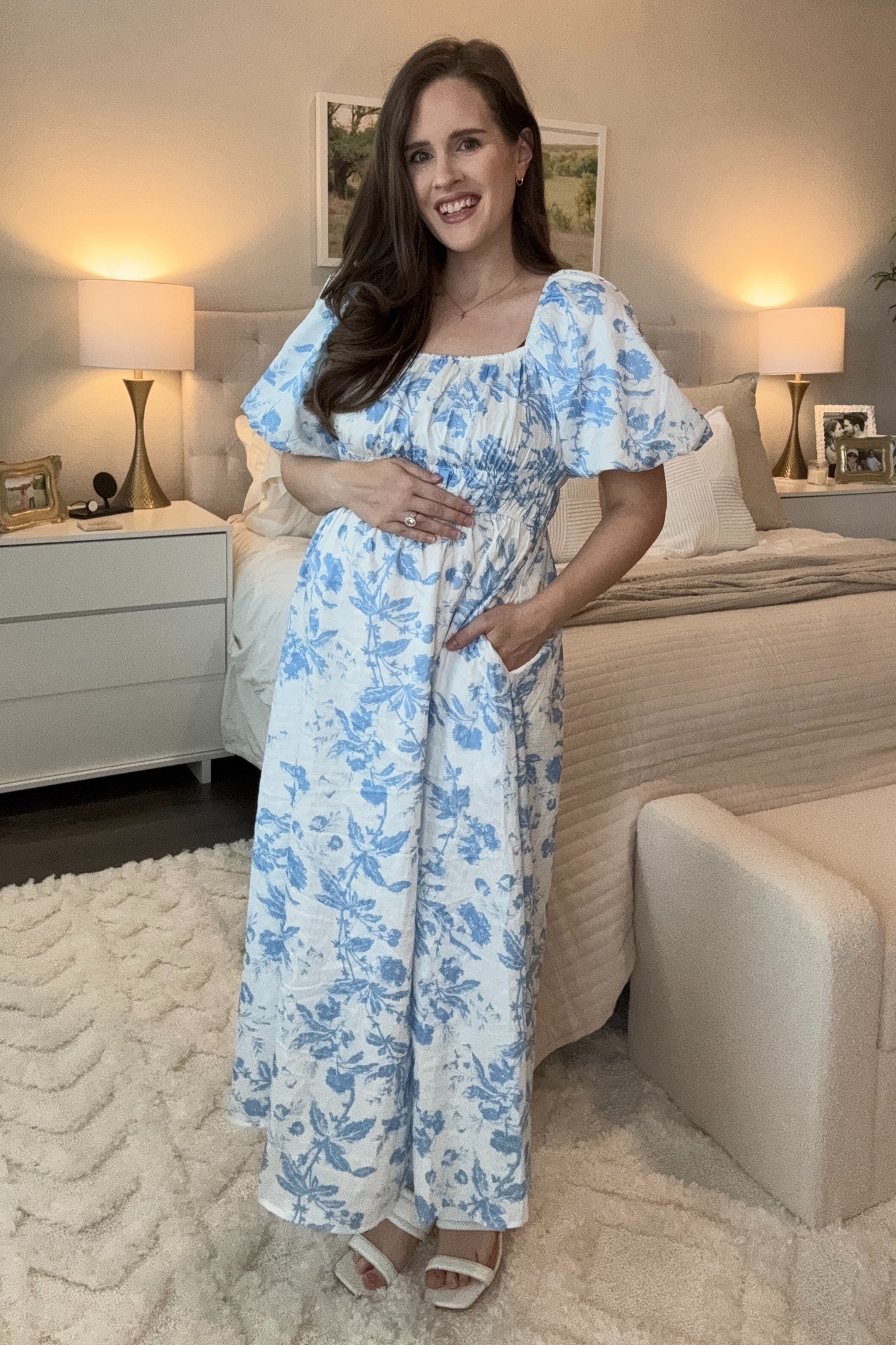woman wearing a light blue floral maternity maxi dress and holding her baby bump