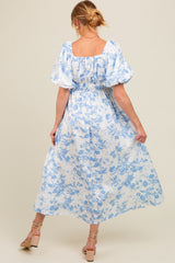 woman wearing a blue floral print maxi maternity dress with puff sleeves, showing her baby bump from the back