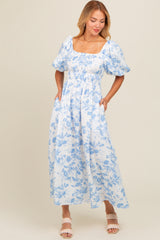 woman wearing a blue and white floral maxi dress with puff sleeves and pockets