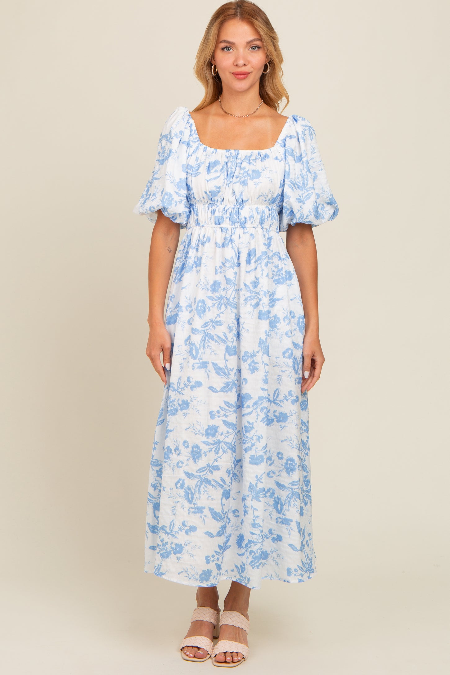 woman wearing a light blue floral maxi dress with puff sleeves and a square neckline