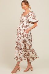 woman wearing a floral print maternity dress with puff sleeves and a flowy skirt, showcasing a baby bump