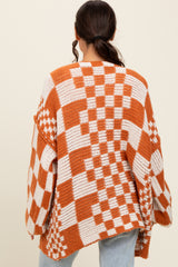 woman wearing an oversized orange and white checked sweater with long sleeves and a relaxed fit from the back