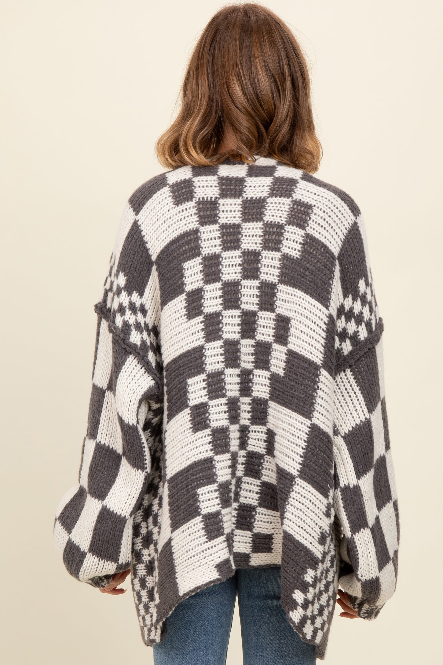 woman wearing a gray and white checkered oversized sweater from the back with loose sleeves