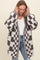 woman wearing a gray and white checkered oversized knitted cardigan over a white t-shirt and blue jeans