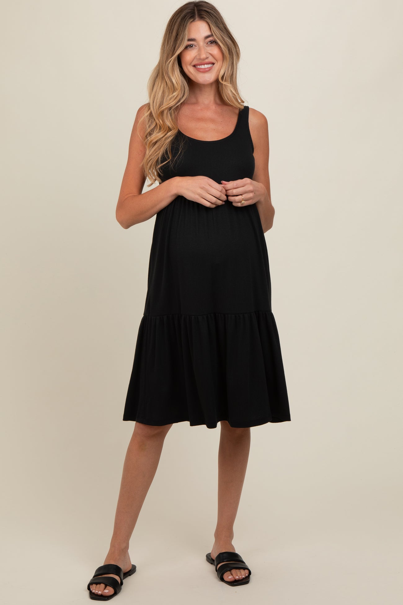 woman wearing a black maternity sundress with a tiered skirt and a visible baby bump