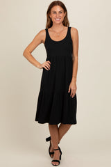 woman wearing a black sleeveless tiered midi dress with a scoop neckline and black heels