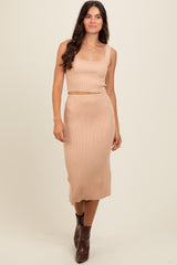 woman wearing a beige ribbed knit crop top and matching midi skirt, styled with brown ankle boots