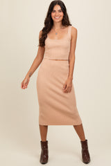 woman wearing a beige ribbed knit crop top and matching midi skirt with fitted silhouette and brown ankle boots