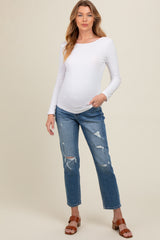 woman wearing a white long sleeve maternity top and distressed blue jeans, showing her baby bump