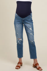 woman wearing dark blue maternity jeans with a high waistband and distressed details, paired with brown heeled sandals
