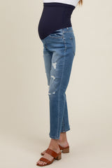 woman wearing distressed light blue maternity jeans with a dark blue over-the-bump waistband and brown block-heeled sandals