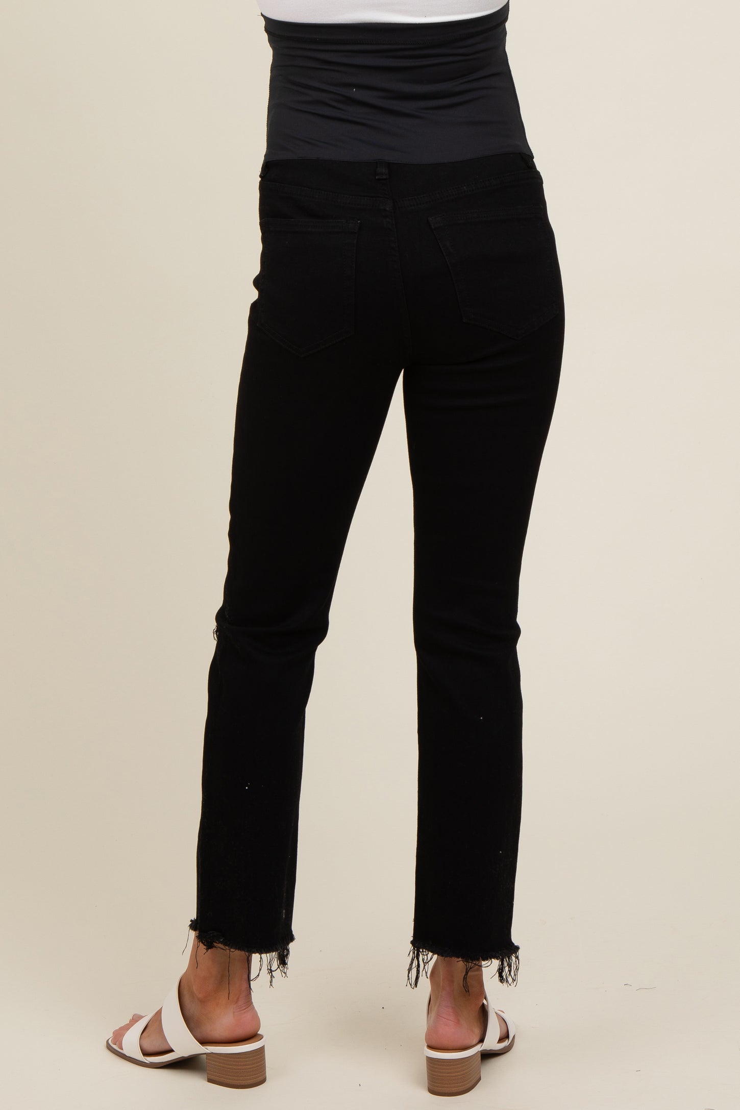 woman wearing black maternity jeans with a frayed hem, showing her pregnant belly from the back