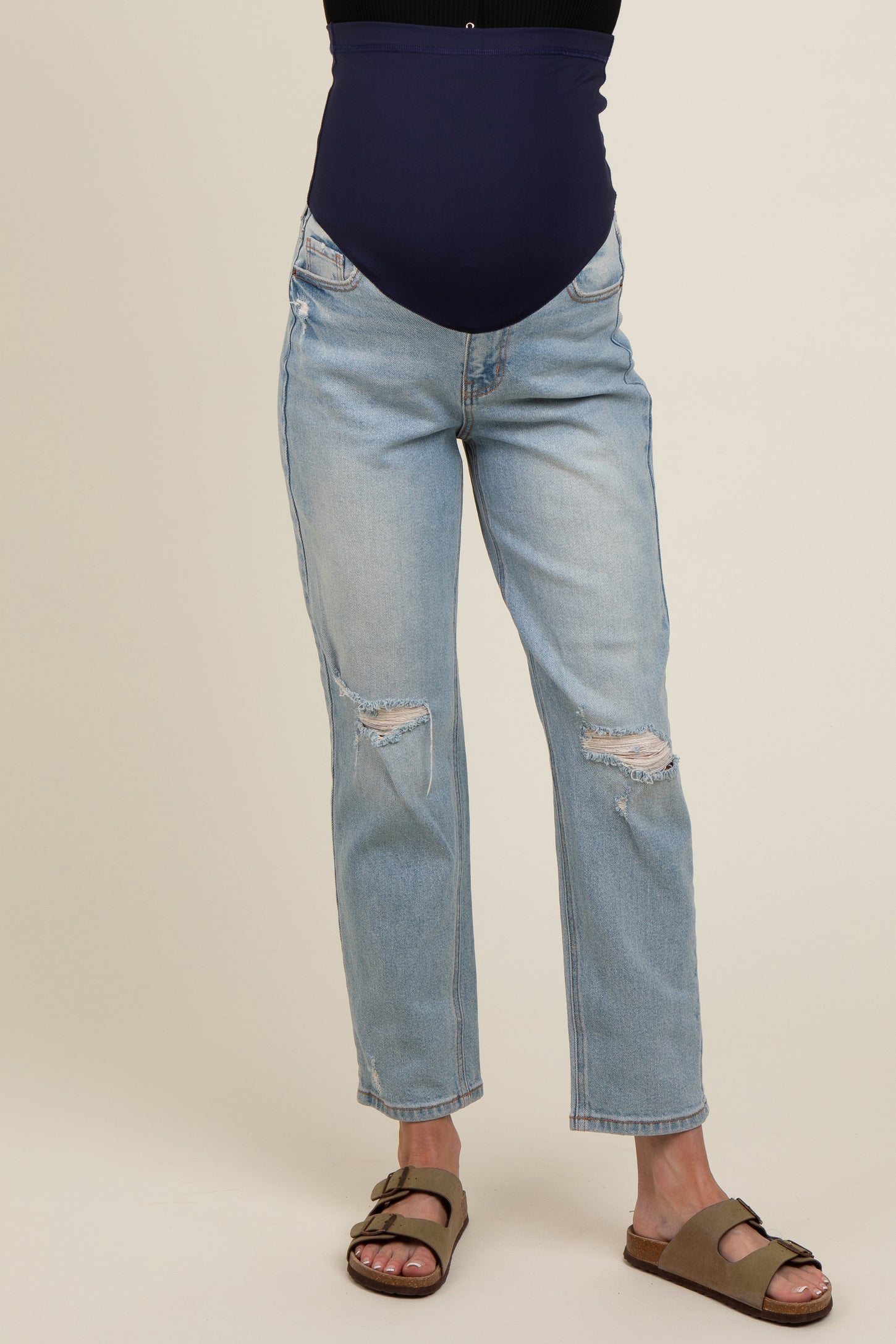 woman wearing light blue distressed maternity jeans with a navy blue over-the-bump waistband