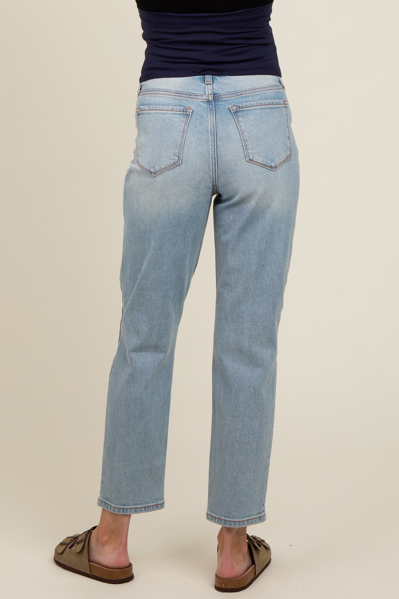 woman wearing light blue maternity jeans, showing the back view, with a snug fit and straight leg style