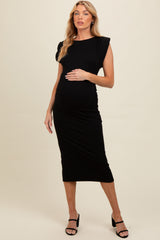 woman wearing a black maternity midi dress with cap sleeves and a visible baby bump
