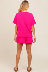 woman wearing a bright pink ribbed t-shirt and matching shorts, viewed from the back