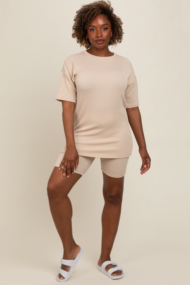 woman wearing a beige ribbed short sleeve top and matching shorts, standing with one hand on her hip