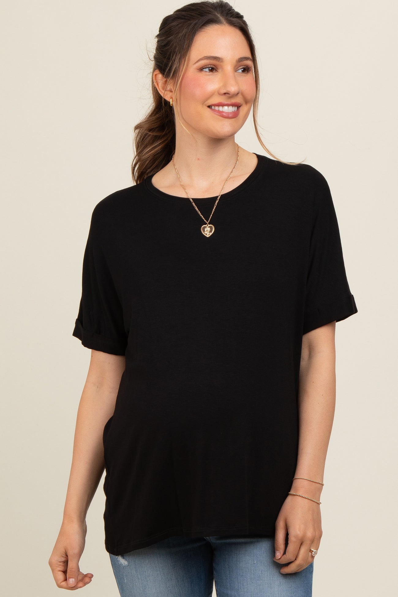 woman wearing a black short sleeve maternity top with rolled cuffs and a baby bump visible