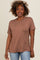 woman wearing a brown short sleeve t-shirt with rolled cuffs and relaxed fit, smiling at the camera