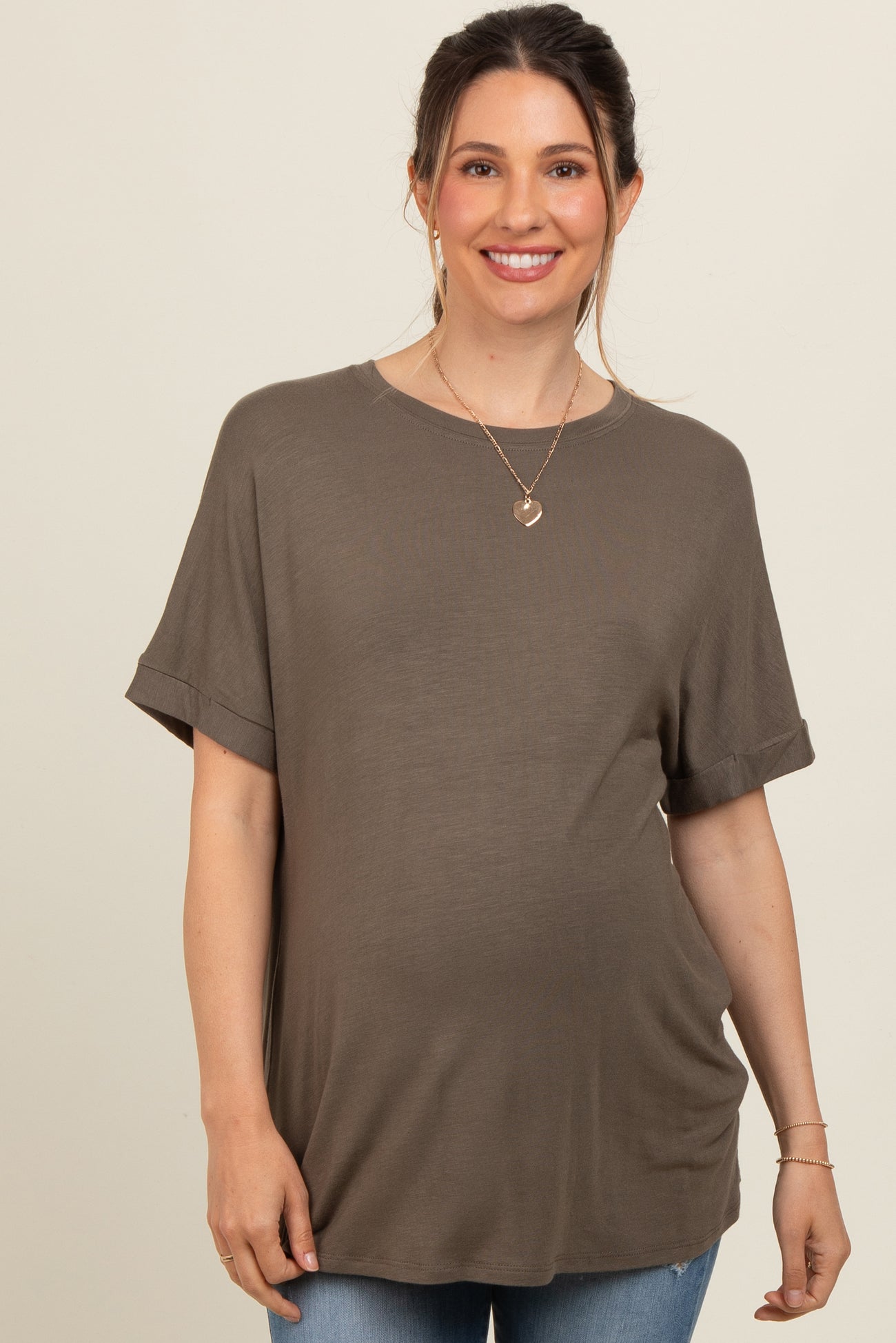 woman wearing a dark olive green short sleeve maternity top and showing her baby bump