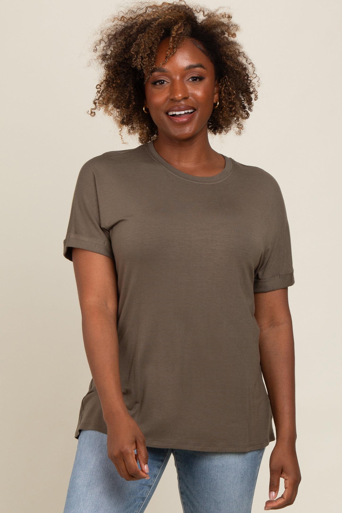 woman wearing an olive green short sleeve t-shirt with rolled sleeves and relaxed fit, paired with light blue jeans