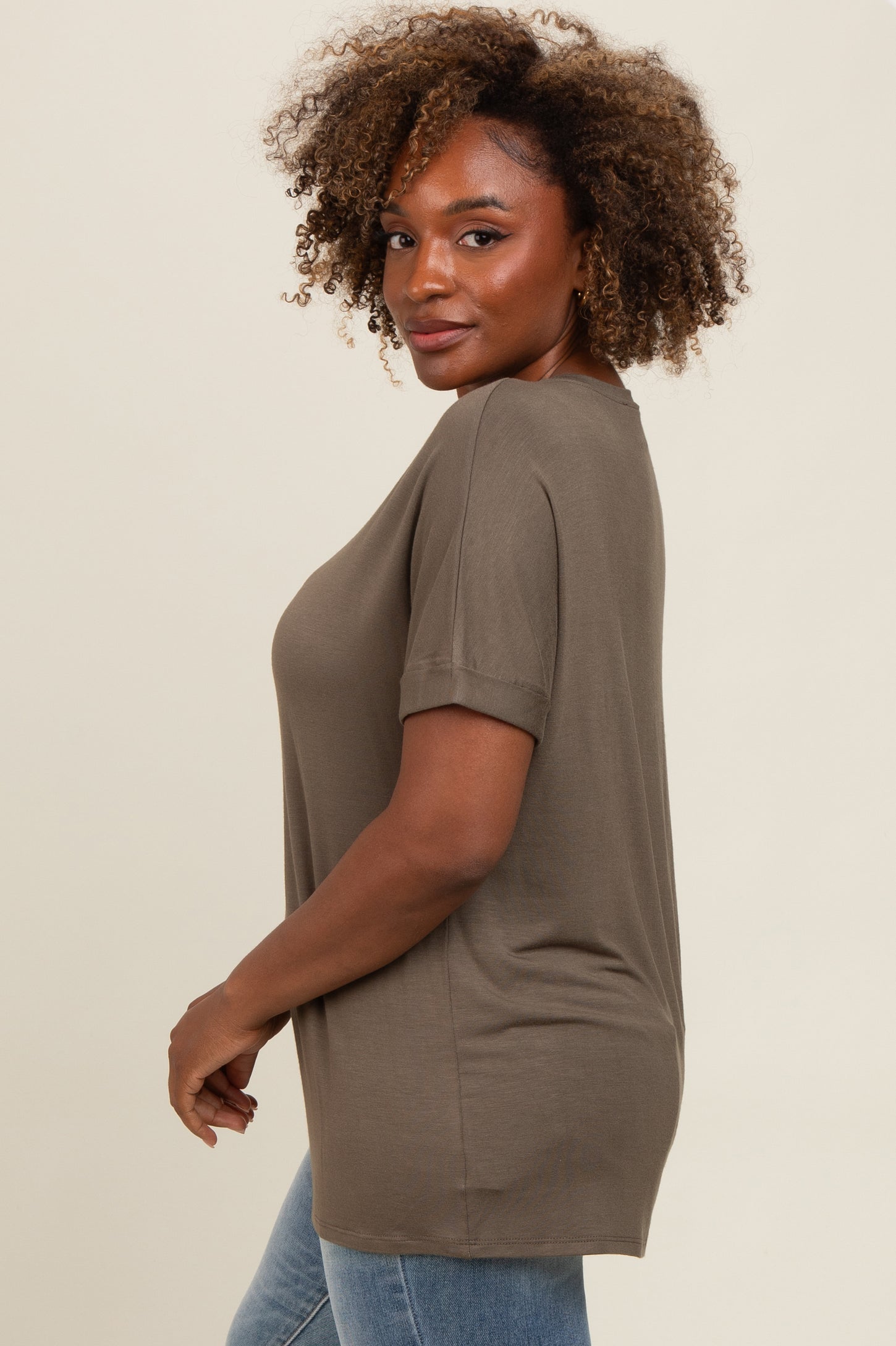woman wearing an olive green short sleeve oversized top with rolled sleeves and styled hair