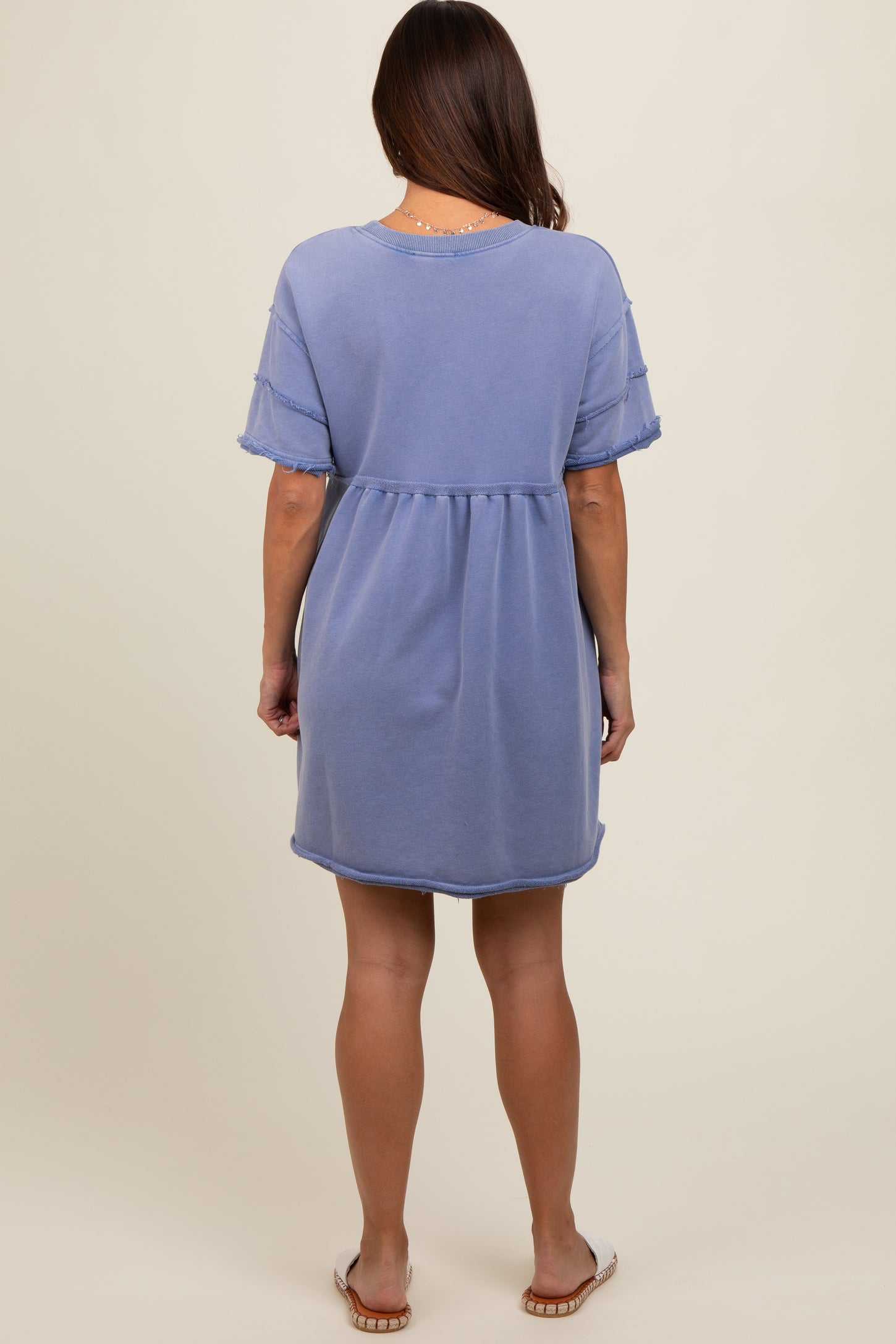 woman wearing a light blue short sleeve maternity dress with a relaxed fit and frayed hem