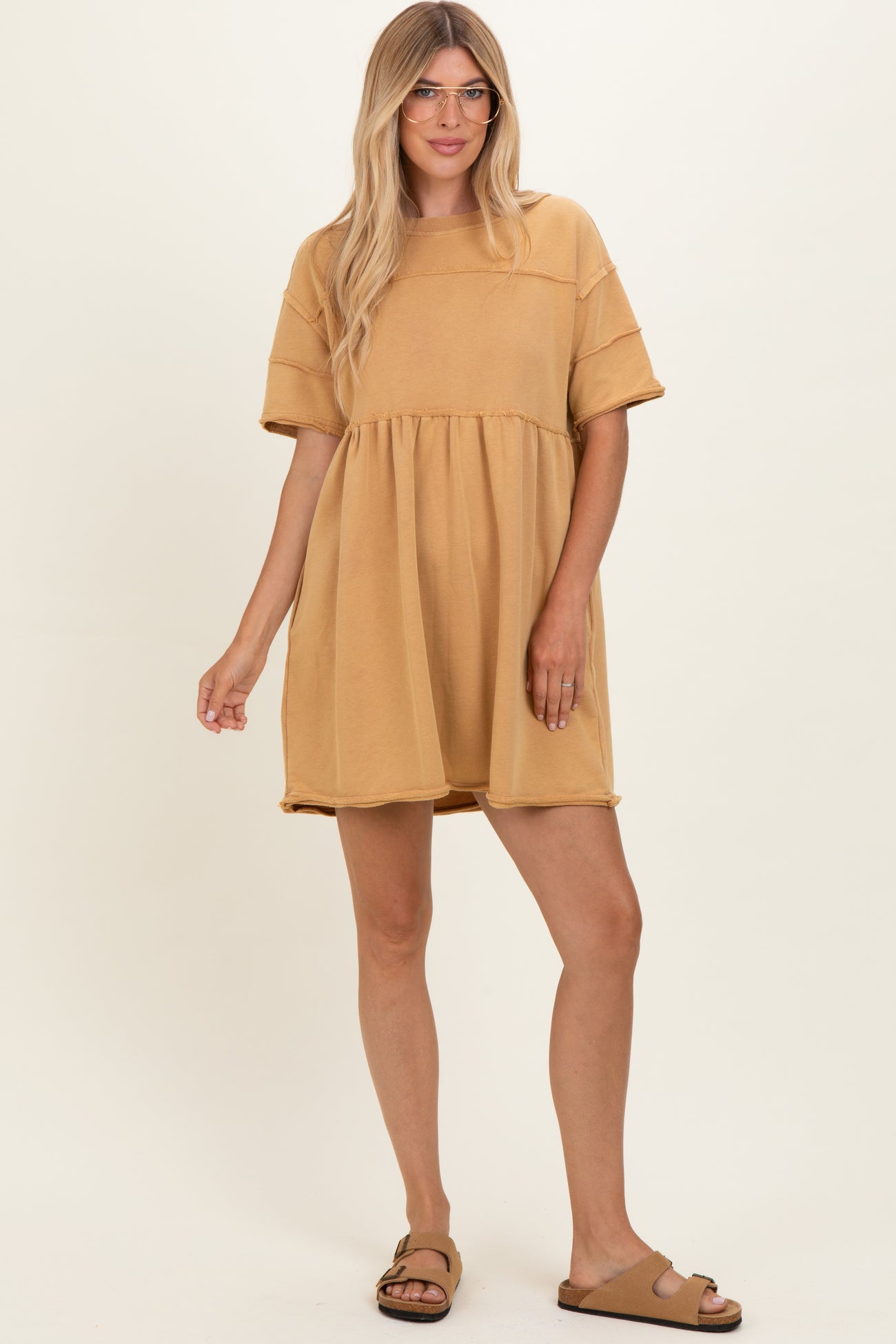 woman wearing a mustard yellow short sleeve babydoll dress with a relaxed fit and round neckline