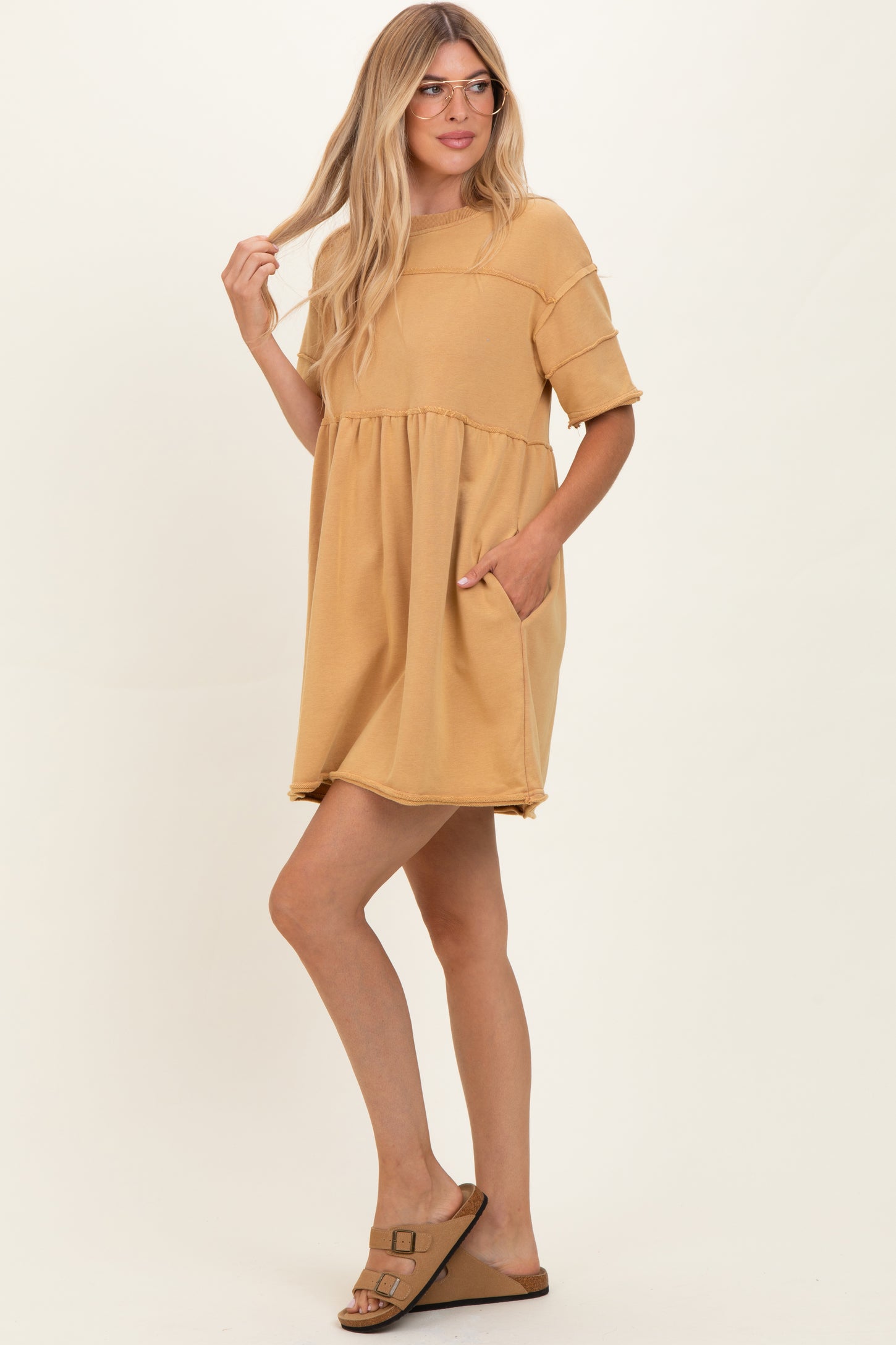 woman wearing a mustard yellow short sleeve dress with a tiered skirt and side pockets, styled with glasses and sandals