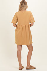 woman wearing a mustard yellow short sleeve dress with a gathered waist and rounded hem, seen from the back
