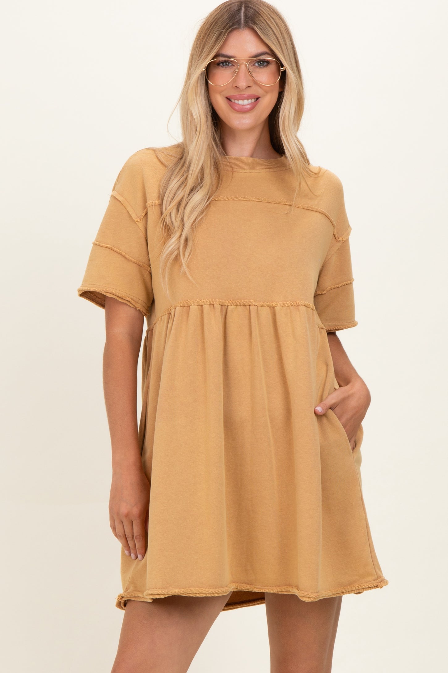 woman wearing a mustard yellow oversized short sleeve dress with a cinched waist and pockets