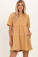 woman wearing a mustard yellow oversized short sleeve dress with a cinched waist and pockets