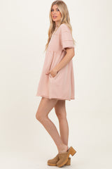 woman wearing a light pink short sleeve oversized dress with pockets and a relaxed fit
